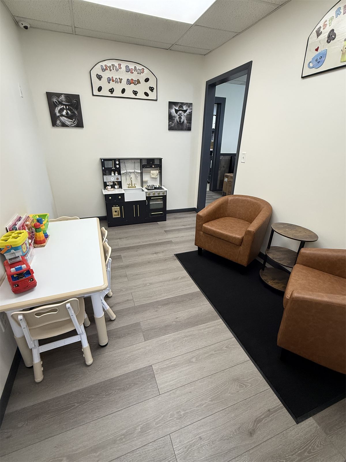 The Little Beans Play Area inside the shop, with a kids' table and toys, a play kitchen, and comfy leather chairs